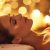 bedazzled woman wearing towel laying down smiling warm background tantra massage hand on chest